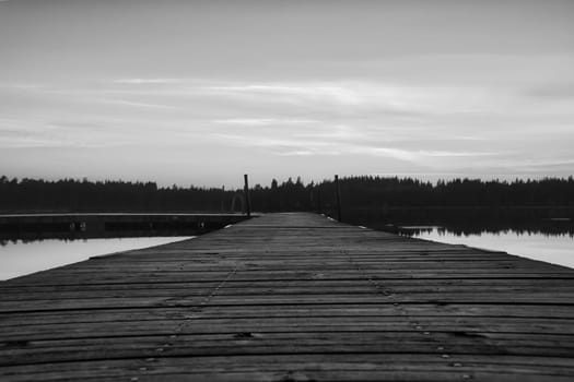 Wooden jetty at sunset on a Swedish lake. Taken in black and white. A bathing lake in the Scandinavian landscape