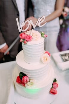 Beautiful big wedding cake with flowers and with the inscription love