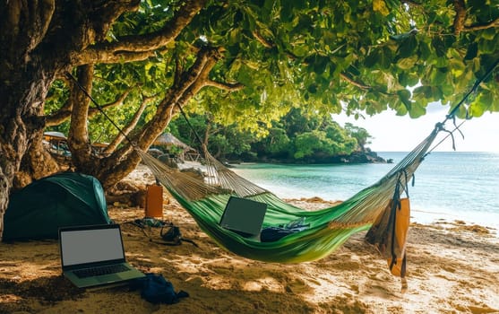 Remote work paradise: Laptop and hammock on a tropical beach with turquoise water, lush trees, and camping gear, illustrating digital nomad lifestyle.