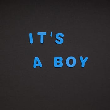Creative blue text made from plastic letters It's a boy writing on black paper background with copy space. Baby shower concept, celebration card template