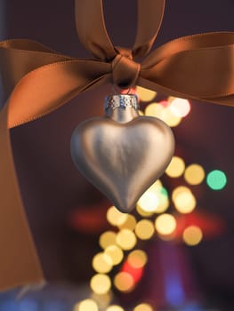 Silver heart shaped Christmas bauble on a blurred Christmas lights background