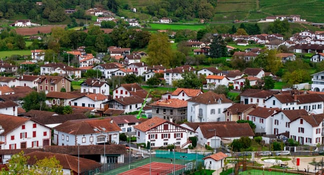 Saint Jean Pied de Port. A lot of houses and a green tennis court. The houses are mostly white and brown