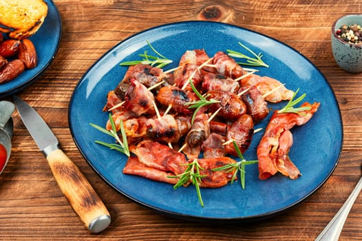 Homemade sweet and savory bacon wrapped dates served on a platter. Rustic style.