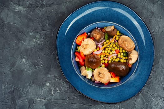 Dietary vegetable salad with marinated pickled mushrooms, green peas in bowl. Space for text.