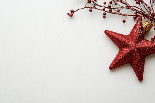 A striking red Christmas star ornament rests alongside decorative berry branches, enhancing the holiday spirit against a pristine background. Perfect for seasonal decor inspiration.