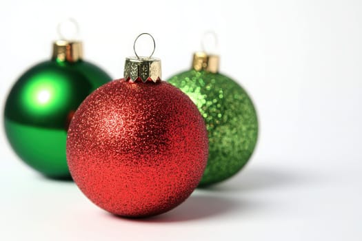 Bright Christmas tree ornaments in vibrant red and green glimmer with festive sparkles, creating a cheerful holiday atmosphere on a pristine white backdrop, perfect for holiday decorating.