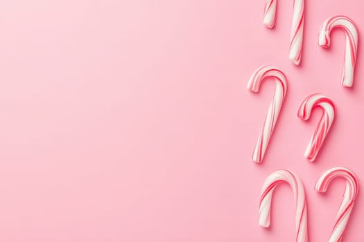 A collection of colorful candy canes is displayed against a soft pink backdrop, evoking a festive and joyful atmosphere perfect for holiday celebrations and sweet treats.