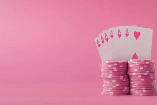 Colorful pink poker chips are carefully stacked to form a pyramid, accompanied by playing cards that feature heart symbols, showcasing a playful and vibrant poker setting.