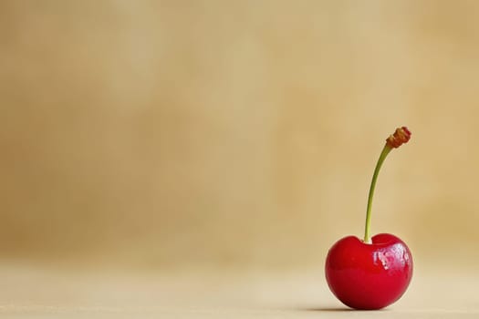A vibrant red cherry rests on a smooth beige surface, emphasizing minimalism and highlighting the fruits glossy surface and delicate stem, perfect for a fresh and clean aesthetic.