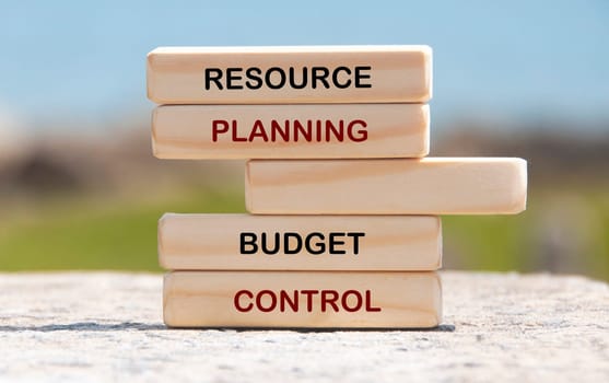 Resource planning and budget control text on wooden blocks with blurred nature background.