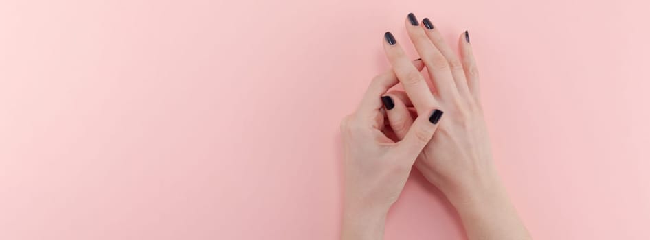 Stylish trendy female black manicure. Beautiful young woman's hands on millennial pink pastel background. Beauty and SPA concept. Banner Template for feminine blog social media