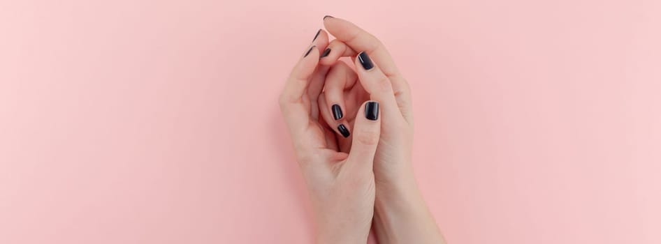 Stylish trendy female black manicure. Beautiful young woman's hands on millennial pink pastel background. Beauty and SPA concept. Banner Template for feminine blog social media