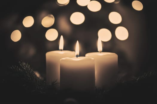 Three lit candles create a warm ambiance against a backdrop of softly blurred lights evoking a tranquil winter evening atmosphere.