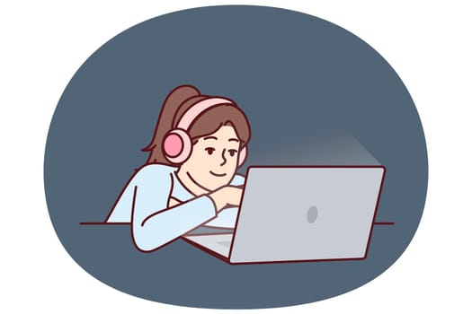 Little girl in headphones uses laptop watching children series or internet show for schoolchildren