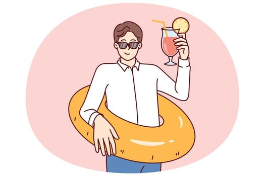 Business man preparing for vacation and tropical travel, holding inflatable ring and cocktail. Businessman in sunglasses on business trip on sunny island resting forgetting about work