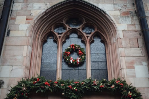 A beautiful wreath adorned with red ribbons hangs on a church window surrounded by lush greenery capturing the festive spirit of the season.