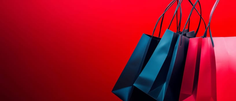 Stylish shopping bags in blue, navy, and pink colors arranged on vibrant red background with copy space, perfect for sale or retail concepts.