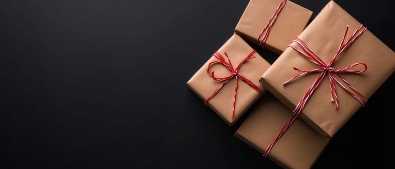 Elegant wrapped presents in kraft paper tied with red and white string, arranged on dark surface with ample space for text or design elements.