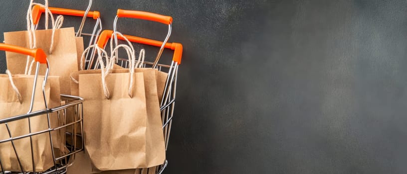 Multiple shopping carts filled with paper bags on a dark background, ideal for retail and commerce themes. Copy space available.