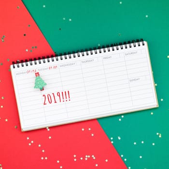 Creative New Year or Christmas timetable event planner mockup flat lay top view Xmas holiday celebration holiday schedule on red green paper background. Template mock up your text design 2019