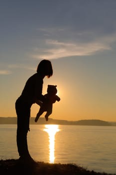 A beautiful and touching silhouette of a loving parent holding their child tenderly against a stunning sunset