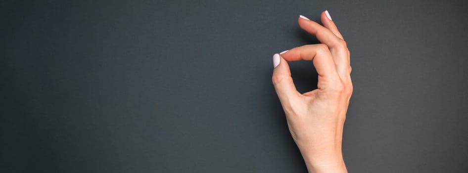 Stylish trendy female pastel pink manicure. Beautiful young woman's hands on black background. Beauty and SPA concept. Template for feminine blog social media