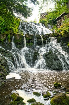 Small waterfall in Sweden. Moss-covered stones. Forest on the river bank. Scandinavian nature