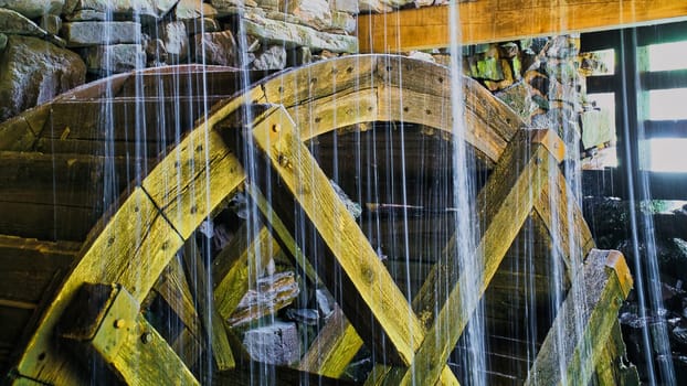Old wooden waterwheel splashed by falling water. Picture from a watermill in Sweden by a stream.