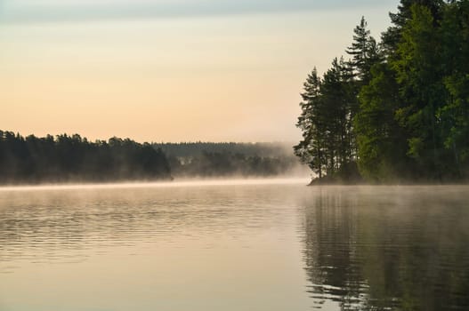 Sunrise with fog forming over a lake in Sweden, at dawn. Romantic silence, in the Scandinavian nature