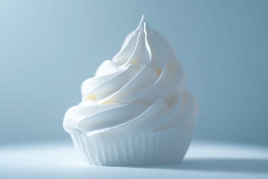 A perfectly crafted whipped cream swirl sits elegantly on a cupcake, showcasing its smooth texture and pristine white color. The soft blue background enhances its minimalist appeal.