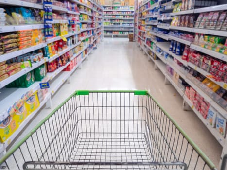 Empty red shopping cart view with warm light, Shopping cart in supermarket, Trolley in department store Abstract blurred of colorful shelves.