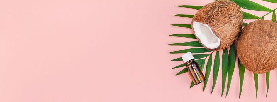 Creative flat lay top view of green tropical palm leaves coconut fruits and coconut oil cosmetics for skin and hair care on pink paper background copy space. Minimal tropical summer beauty spa concept
