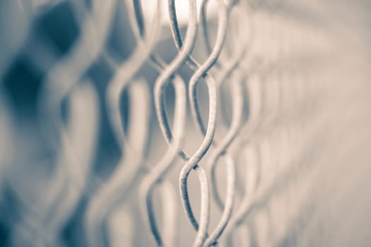 This image shows a close-up of a blurred metal fence with twisted links in focus.