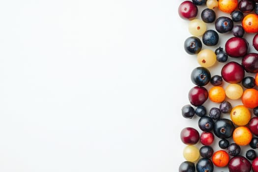 A vibrant collection of assorted berries lies scattered on a pristine white backdrop, highlighting their natural colors and textures. The berries include blueberries, blackberries, and cherries.