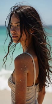 A brunette woman in a swimsuit gazes back while standing near the shoreline. Gentle sea waves lap at her feet under a clear blue sky. Long hair, beautiful young face. Travel and clothing adverts. AI.