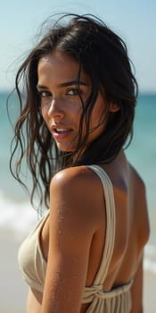 A brunette woman in a swimsuit gazes back while standing near the shoreline. Gentle sea waves lap at her feet under a clear blue sky. Long hair, beautiful young face. Travel and clothing adverts. AI.