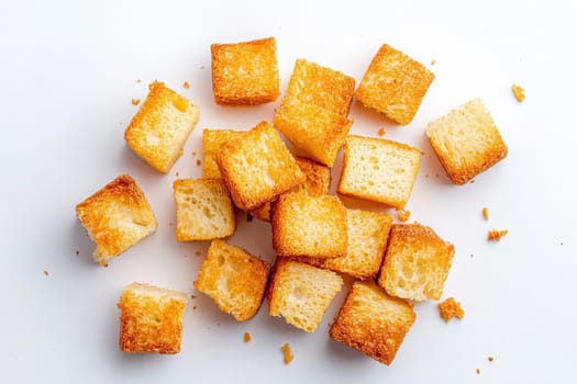 Perfectly golden brown croutons are scattered on a white surface, showcasing their crisp texture. Ideal for adding flavor and crunch to salads, soups, or snack mixes.