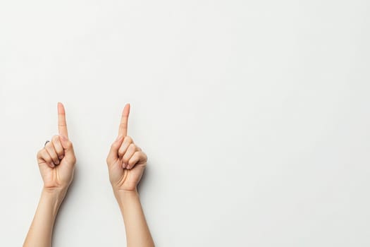 A pair of hands with crossed fingers expresses a gesture of hope and optimism. The hands are positioned against a clean, solid white backdrop, symbolizing positivity and good luck.