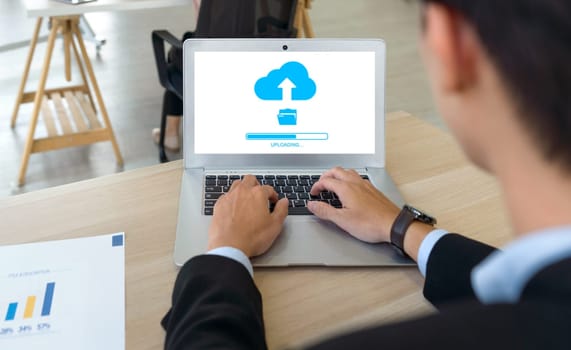 Data storage, networking and internet service concept. Back view of businessman using cloud drive technology upload save files to internet.