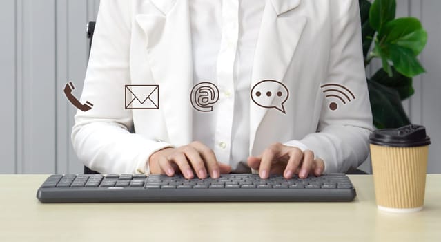 Contact us or Customer support hotline people connect. Businesswoman typing on computer keyboard showing symbol of contact icons (email address, live chat, internet wifi).