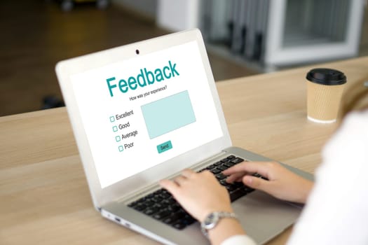 A lady is busy typing on her laptop computer which shows a feedback form on its screen.