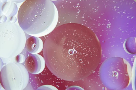 Extreme close up of oil bubbles on water surface with multicolored gradient background. Suitable for design and wallpaper