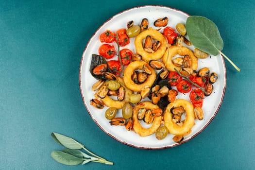 Gourmet steamed mussels with sage herb and deep fried squid rings. Roasted mixed seafood.