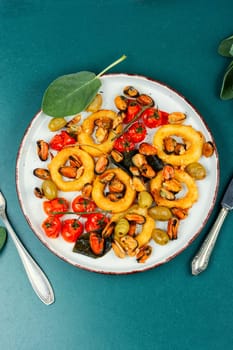 Gourmet steamed mussels with sage herb and deep fried squid rings. Roasted mixed seafood.