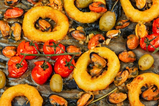Gourmet steamed mussels with sage herb and deep fried squid rings. Roasted mixed seafood.