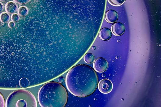 Extreme close up of oil bubbles on water surface with blue and maroon color background. Suitable for design and wallpaper