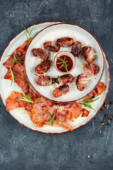 Bacon wrapped date skewers placed, English traditional snack on rustic wooden table. Space for text.