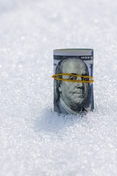 A roll of real cash standing on a snow surface at sunny winter day.