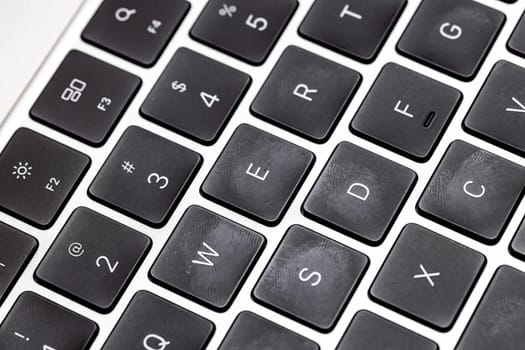 keyboard of famous silver colored laptop with fingerprints, closeup