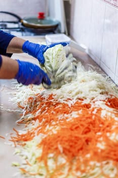 hands in blue gloves cutting cabbage with special double blade slit cabbage shredder knife during sauerkraut preparation